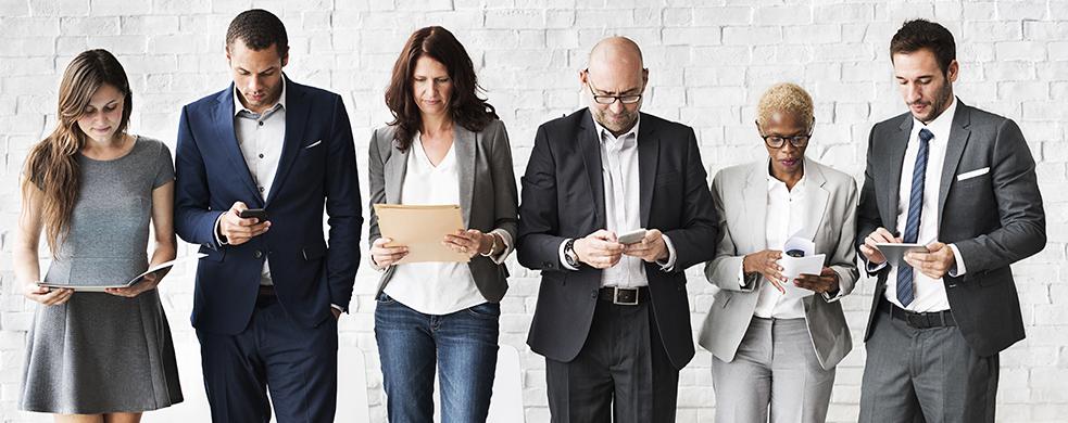 Group of diverse businesspeople reading on their devices or paperwork